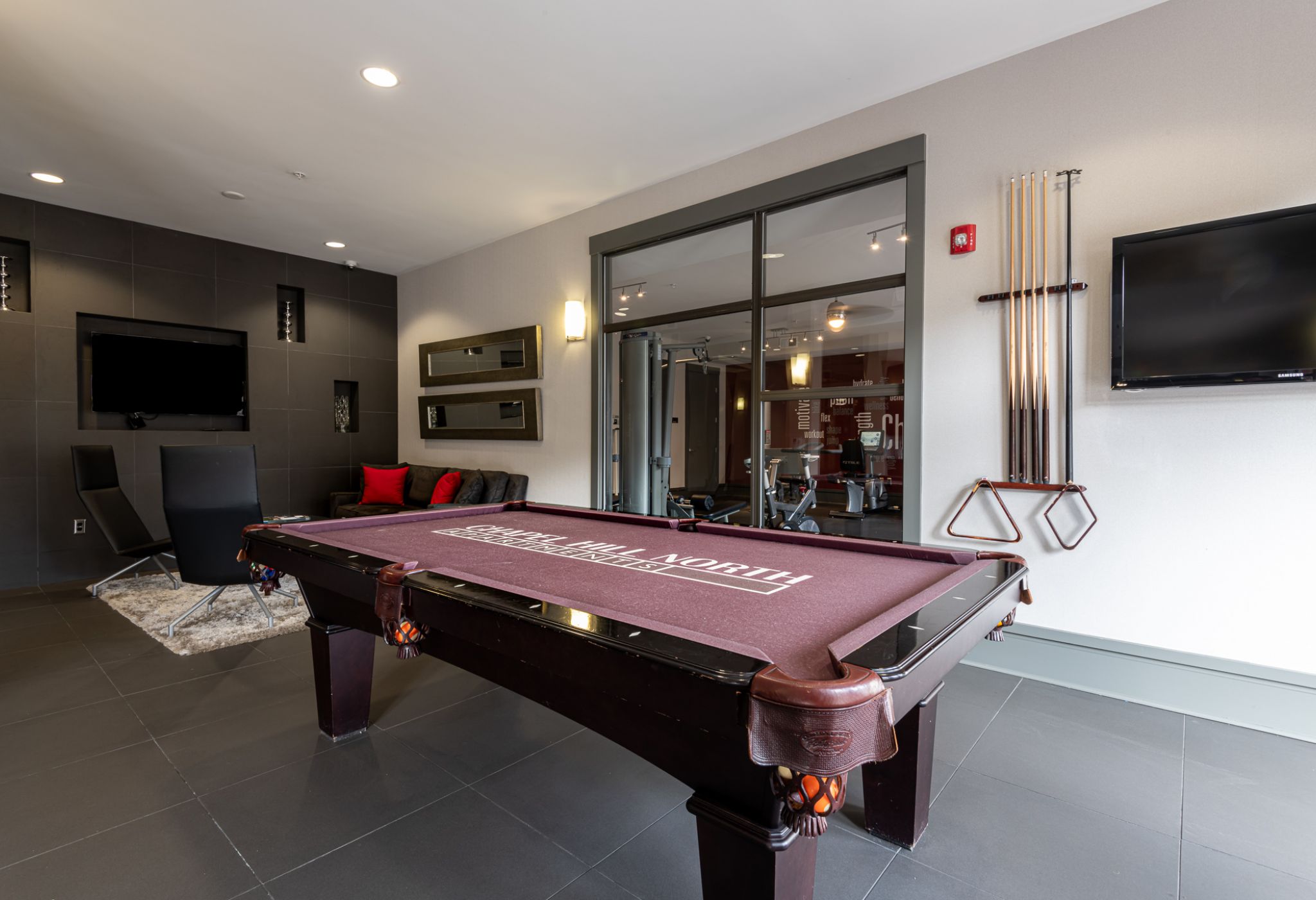 Chapel Hill North apartments club room with pool table in the middle and tv on the left wall
