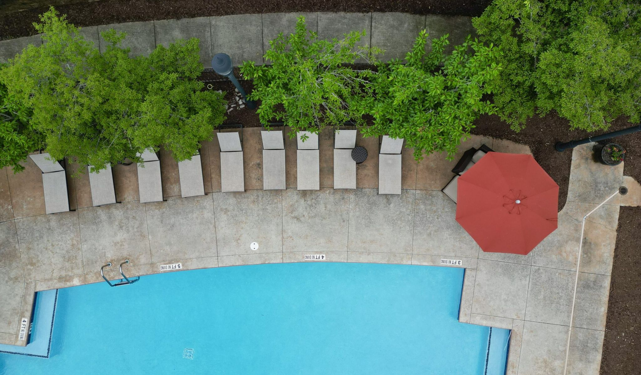 Chapel Hill North Apartments resort style pool with seating around the pool and view of apartments in the background