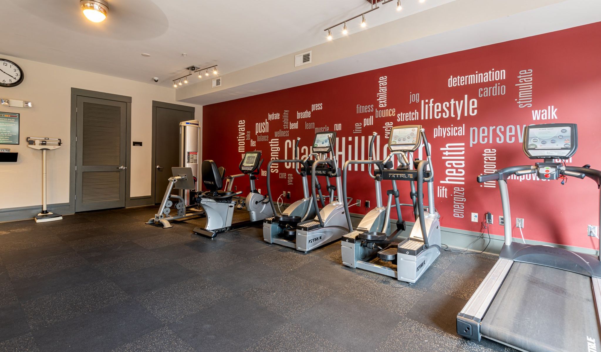 Chapel Hill north apartments resident fitness center with cardio equipment next to a wall with a fitness themed mural