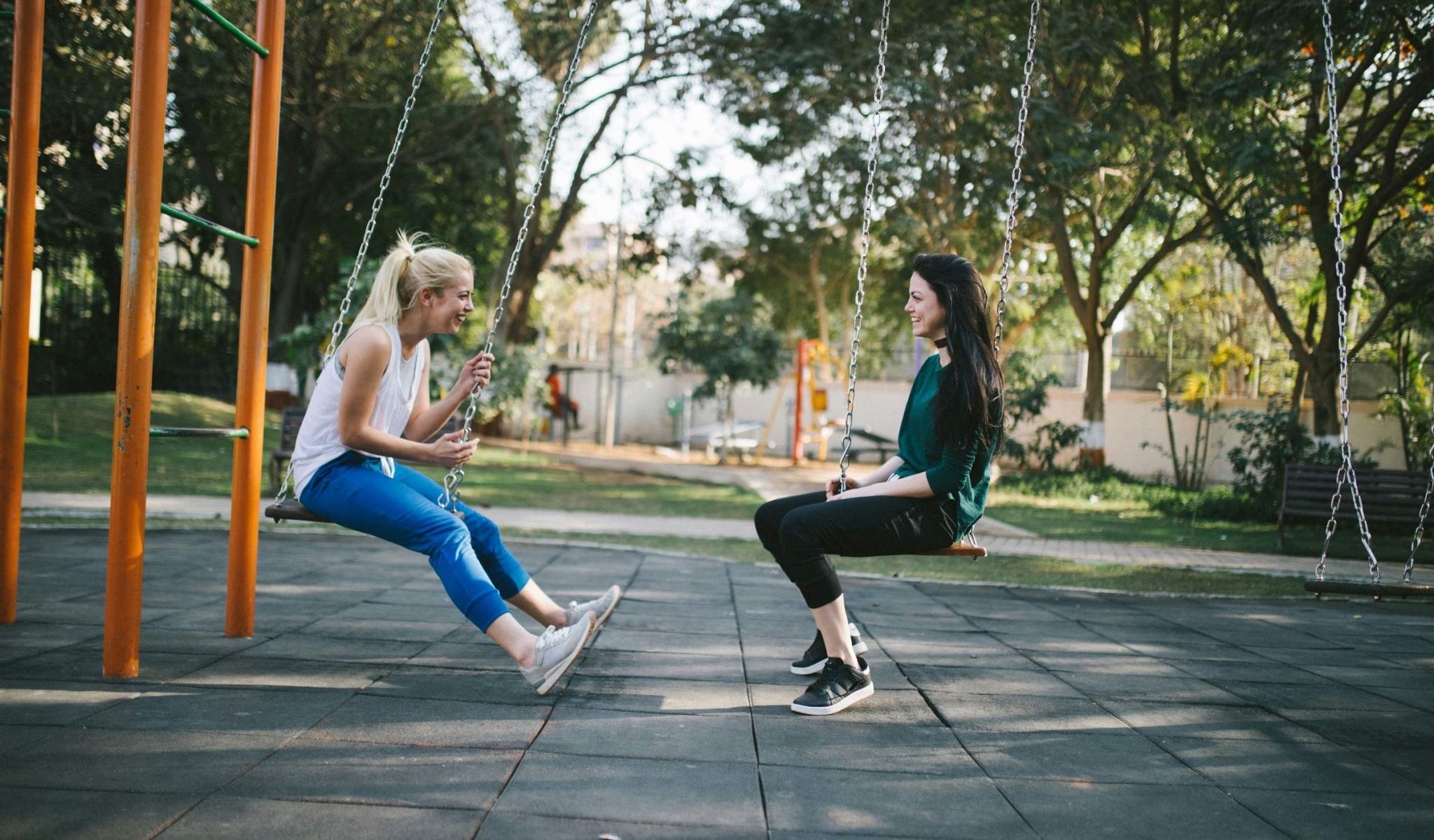 two women on a swing set at a park near chapel hill north apartments