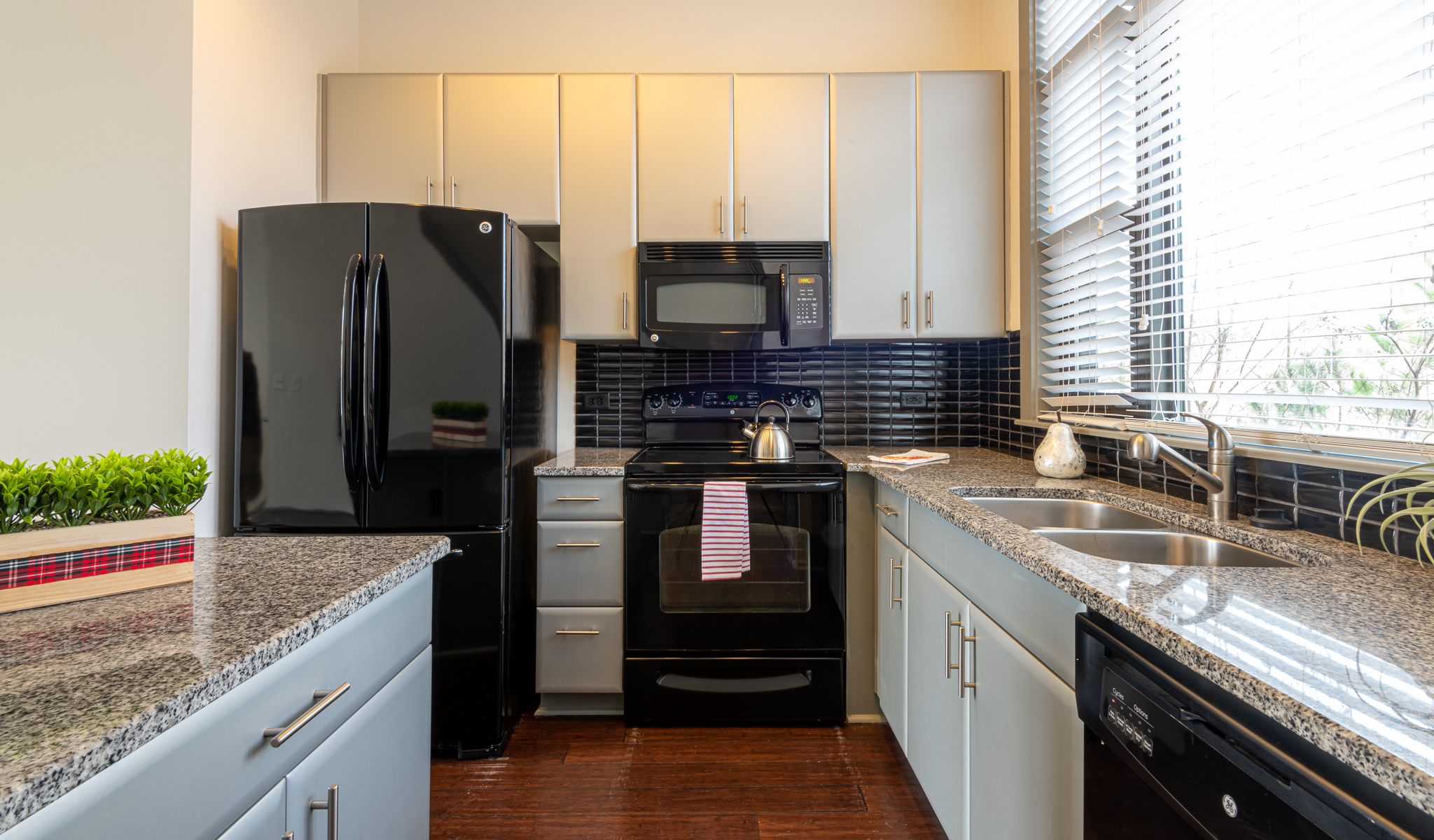 Chapel Hill North apartments custom kitchen cabinetry in luxury apartment kitchen with hardwood floor and black appliances 