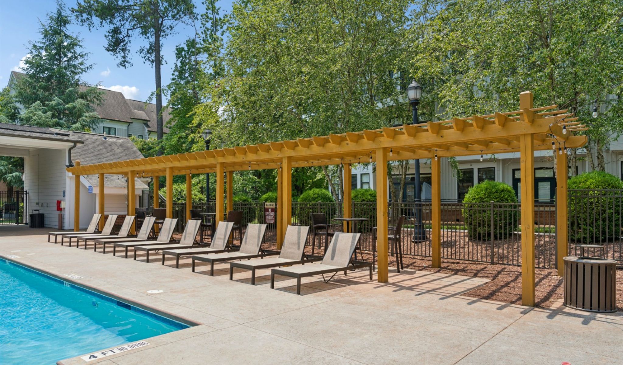 Chapel Hill North Apartments resort style pool with seating around the pool and view of apartments in the background